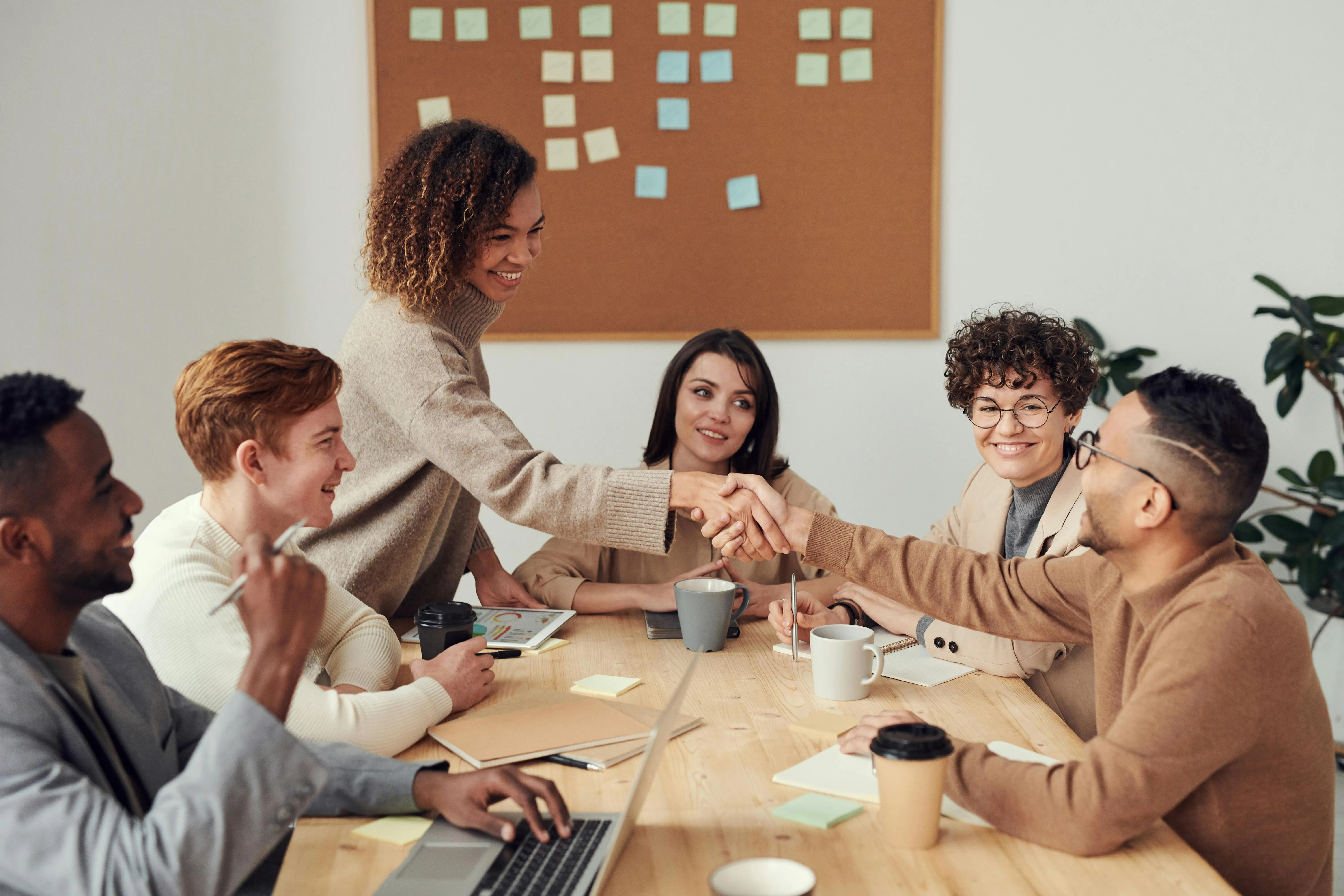 Diverse team of professionals collaborating in a modern boardroom, analyzing charts and planning strategies on a whiteboard.