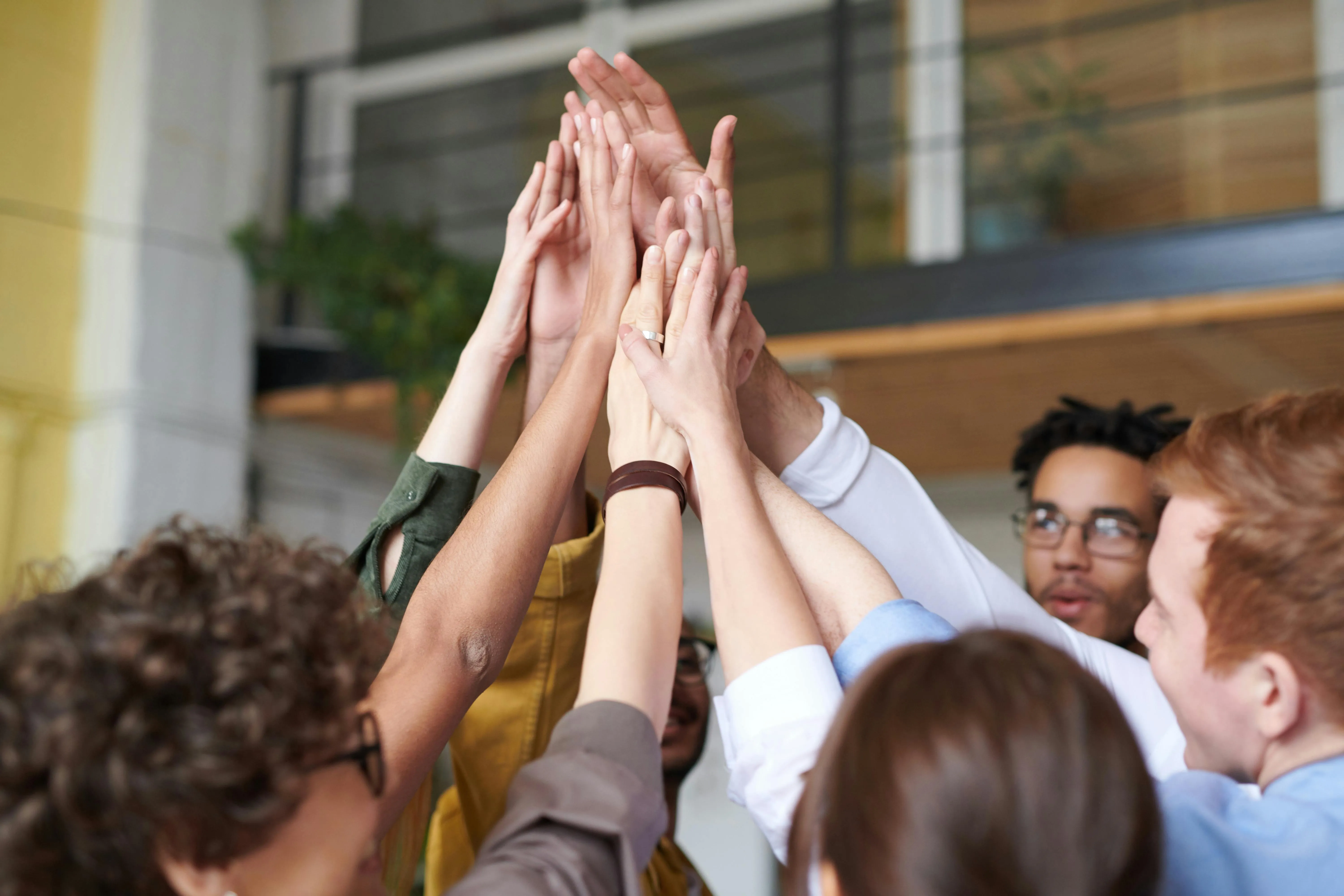 A diverse team of young professionals collaborates with a senior leader in a modern office, analyzing data on a screen.